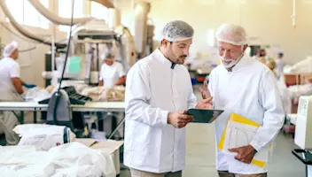 Food factory workers consult the via a tablet.