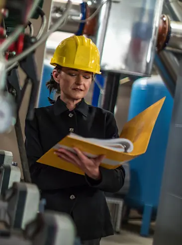 Woman looking at binder in factory.