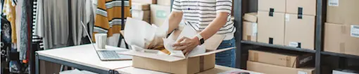 Woman packing clothes for shipping.