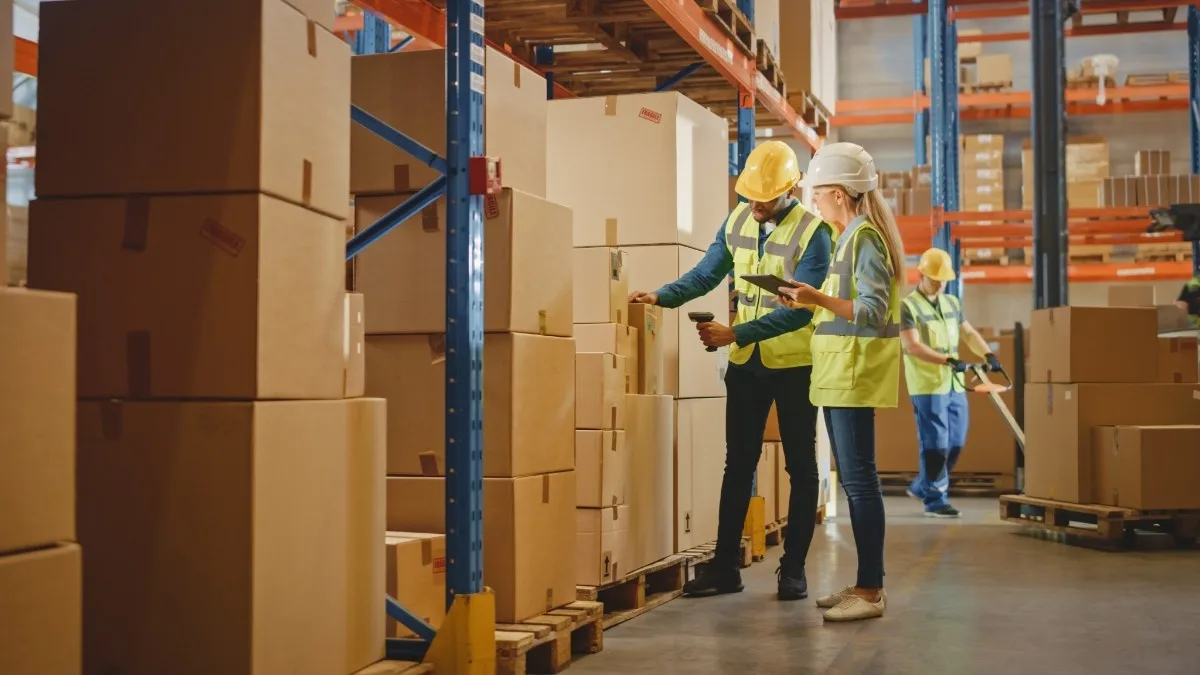 Warehouse supervisor and worker scanning packages with a digital tablet