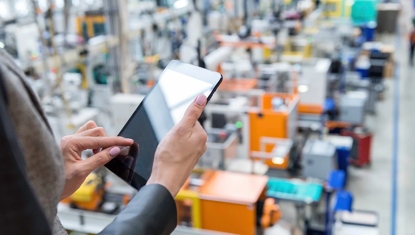 Worker on tablet looking at factory floor