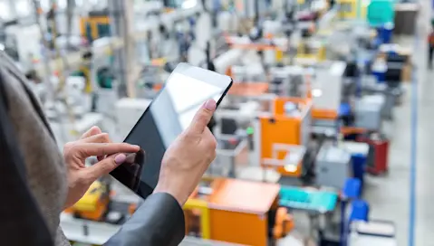 Worker on tablet looking at factory floor