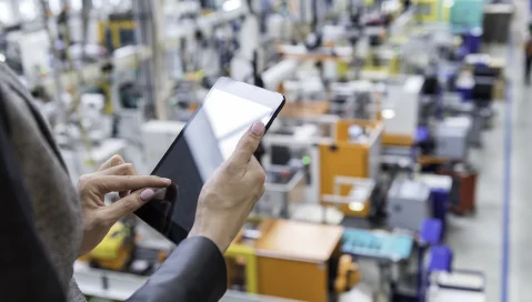 Worker on tablet looking at factory floor