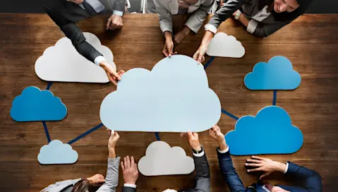 Team sharing cloud image cutouts held over table