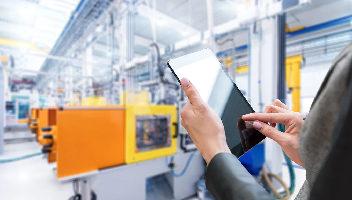 Woman holding smart tablet on a factory floor.