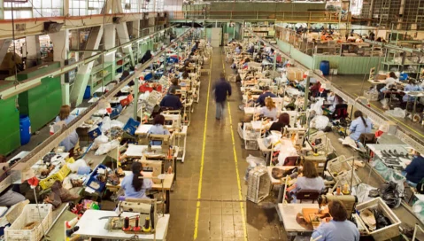 Many people working on sewing machines in a factory.