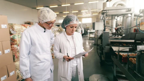 Two food manufacturing professionals study documents.