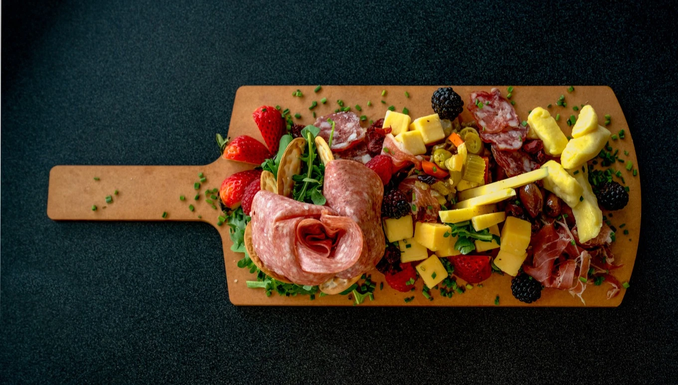 A cutting board laden with fruit and meat.
