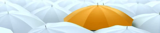 Orange umbrella among white umbrellas