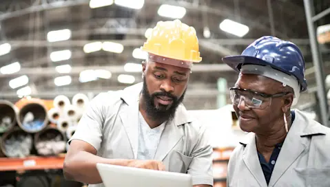 Two people in hardhats looking at tablet