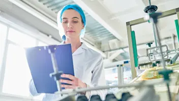 Woman checking in foodfactory compliance.