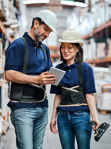 Des employés d'un entrepôt regardant une tablette.