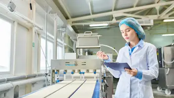 A food facility worker checks notes on a clipboard.