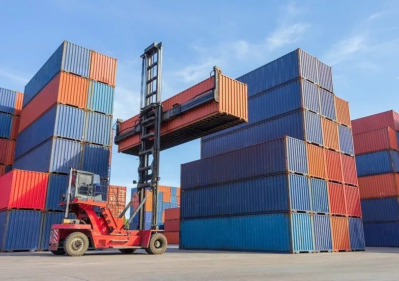 Forklift loading a container box onto a truck in a shipping yard