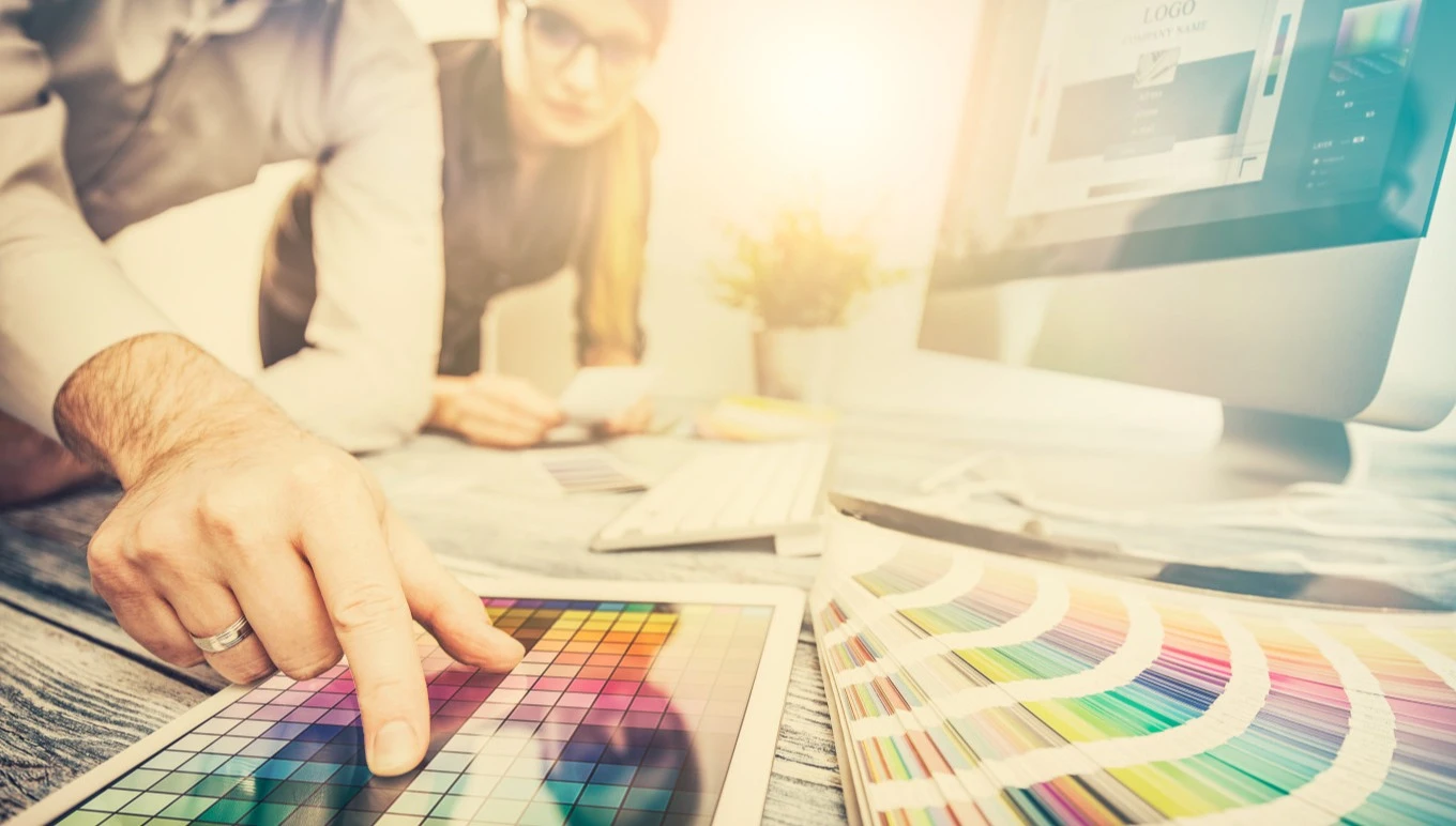 New product development professionals consult color charts while using a PLM system.