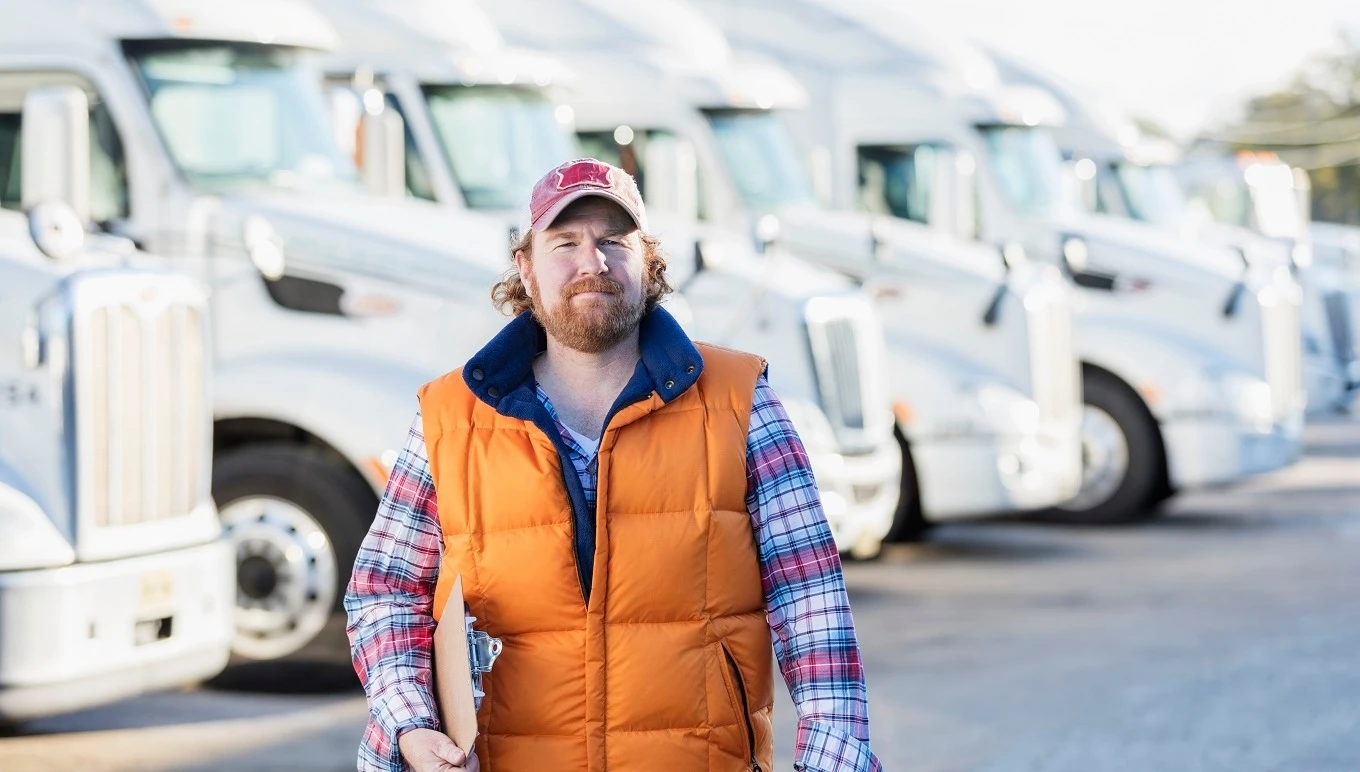 Man walking in parking lot of truck fleet.