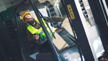 Man in hard hat using forklift truck