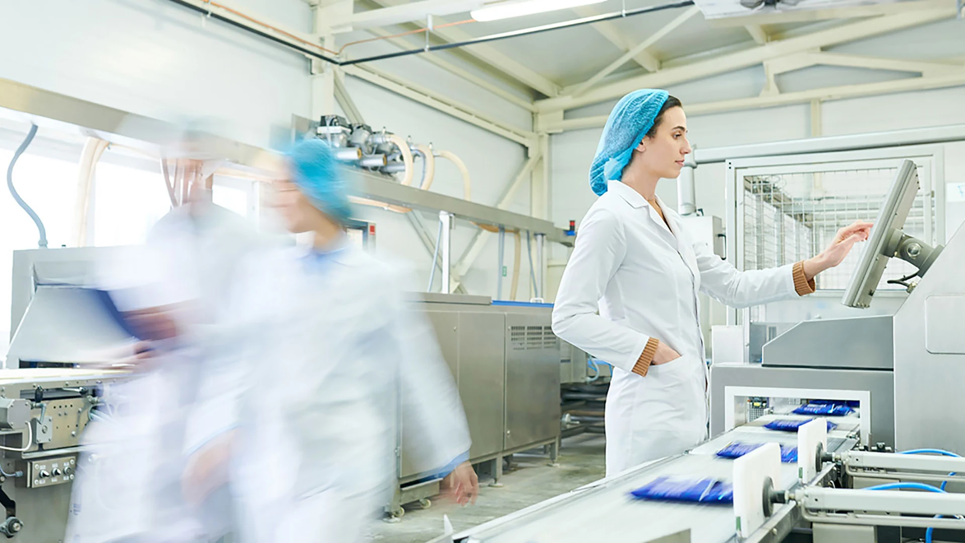 Femme touchant un écran dans une usine.