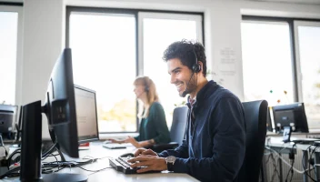 Customer service speaking on the phone in front of computer.