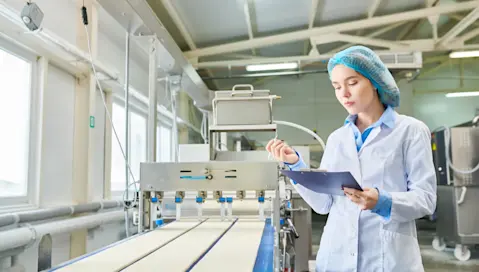 A food manufacturing facility worker records data from product testing.
