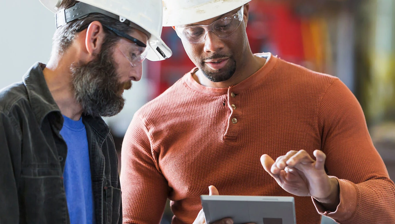 two men in hardhats looking at tablet