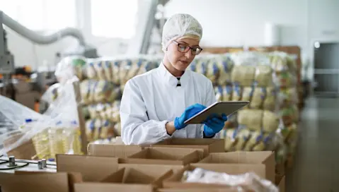 A food distribution worker reviews orders on a tablet.