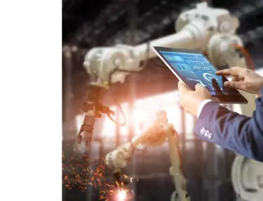 Un homme dans une usine utilisant sa tablette pour contrôler un bras robotique.