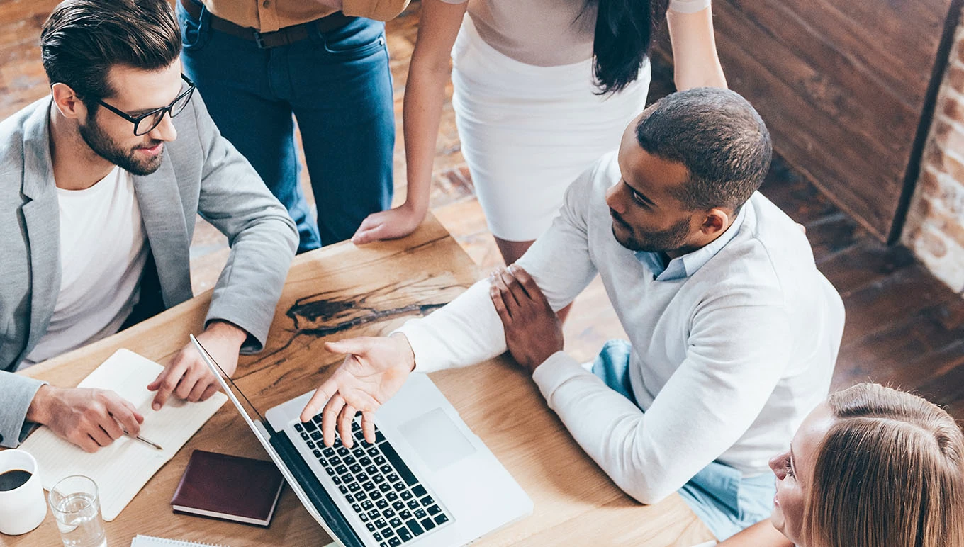  A group of people having a discussion around a laptop