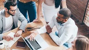  A group of people having a discussion around a laptop