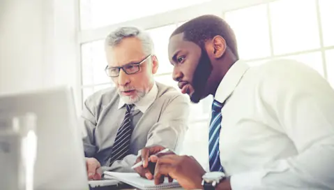 Two men look at same laptop screen