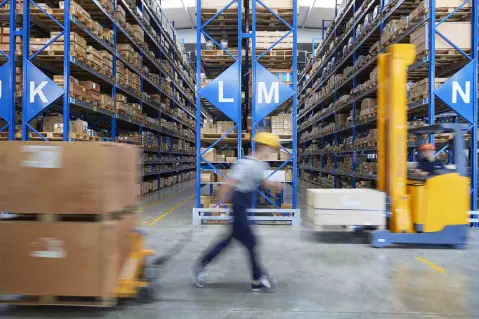Worker moving boxes through storage warehouse