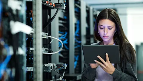 Network engineer in server room reading tablet display