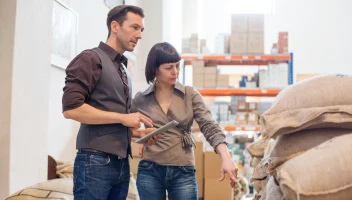 Two food facility workers discuss a shipment.