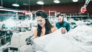 Seamstress with sewing machines on apparel factory floor