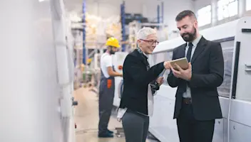 Professionals standing in a factory and using a tablet device