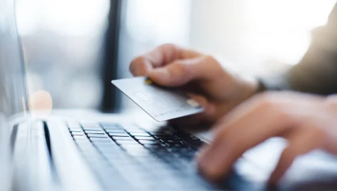 Laptop keyboard and credit card in hand