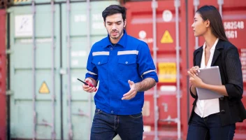 Man and woman walking and talking near shipping containers