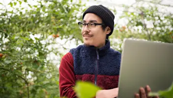 Man on laptop in greenhouse