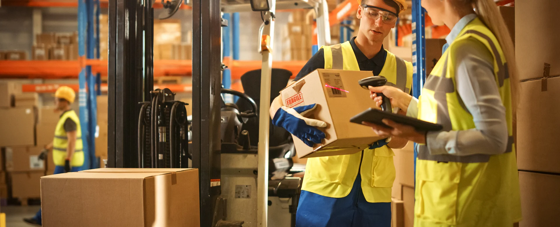 Warehouse manager scanning boxes and coordinating delivery with forklift driver