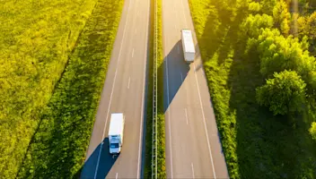 Delivery trucks passing each other on a divided highway.