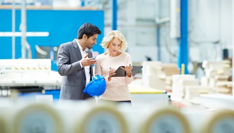 Factory workers reviewing inventory on a tablet