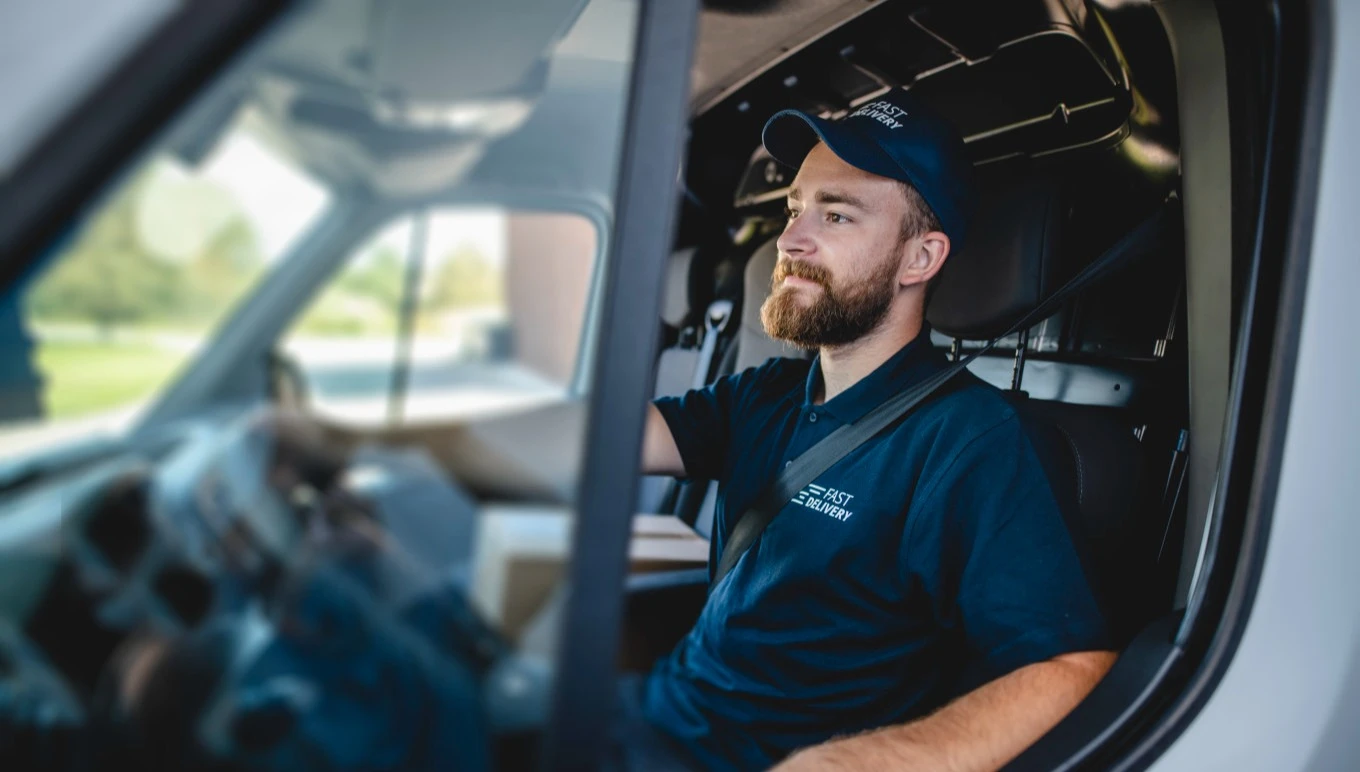 A truck driver looks forward confidently in the cabin of his vehicle.