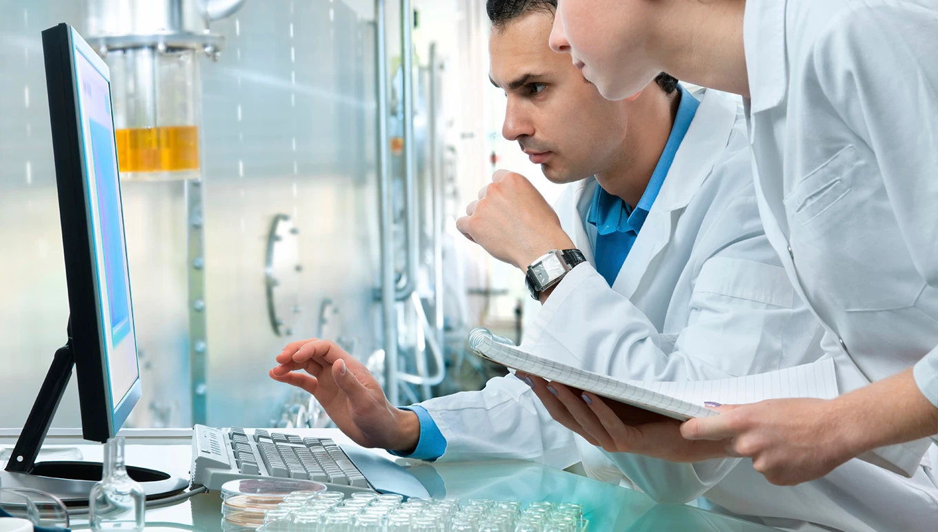 Scientists in lab reviewing computer monitor