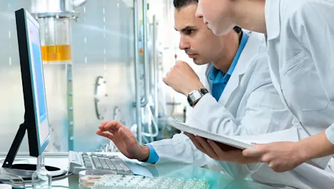 Scientists in lab reviewing computer monitor