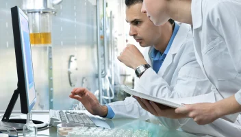 Scientists in lab reviewing computer monitor