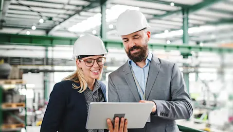 Business professionals in warehouse holding a tablet device