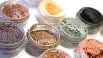 Different shades of eyeshadow in glass containers.