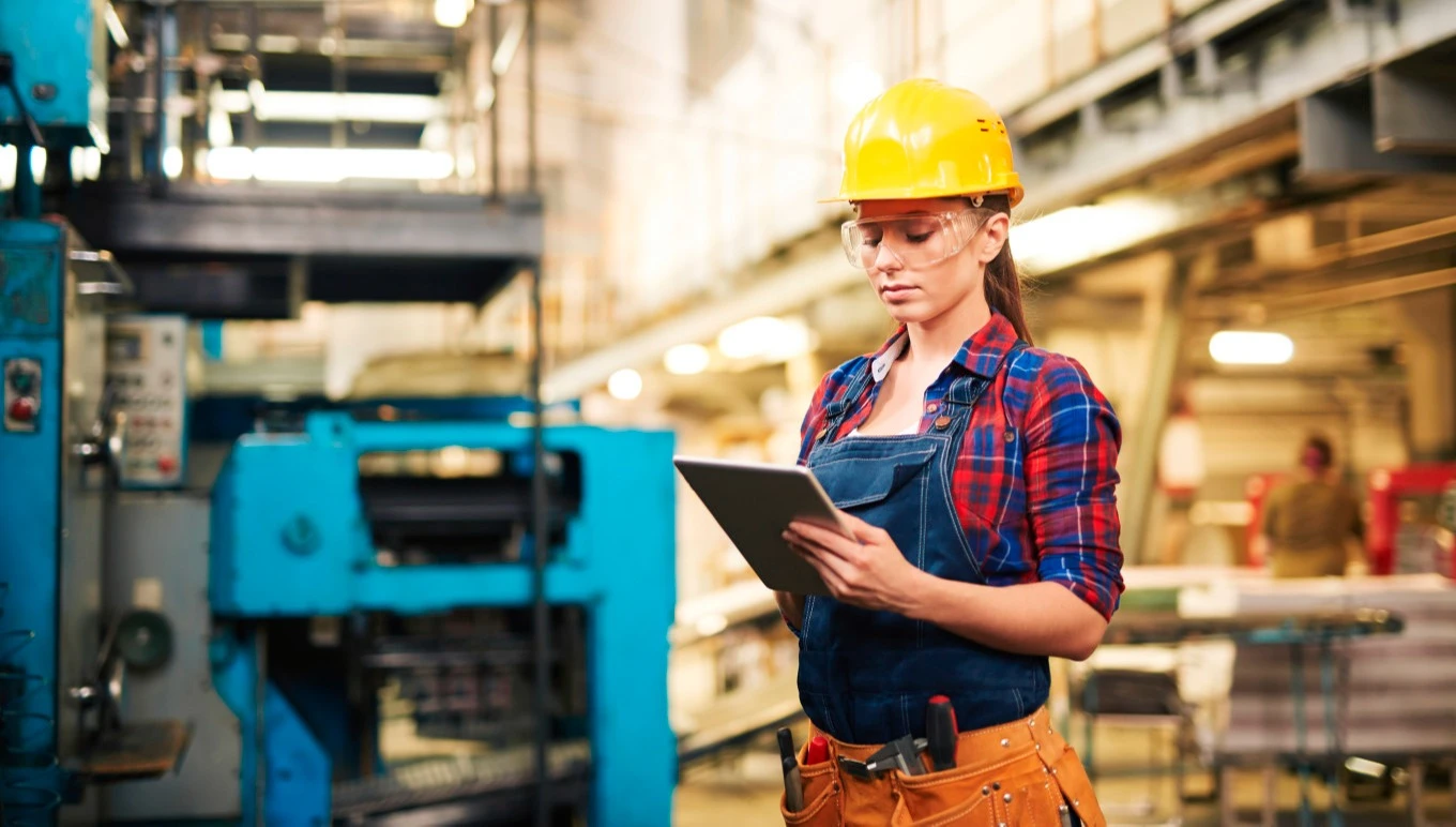 Factory worker in hardhat using touchscreen device.