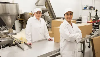 Food distribution facility workers pose in front of loaded boxes.