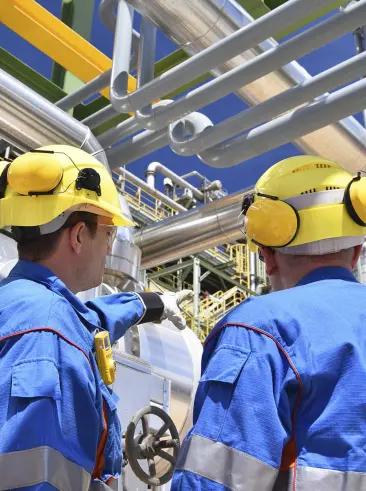 Dos trabajadores de la refinería examinando las líneas de petróleo.